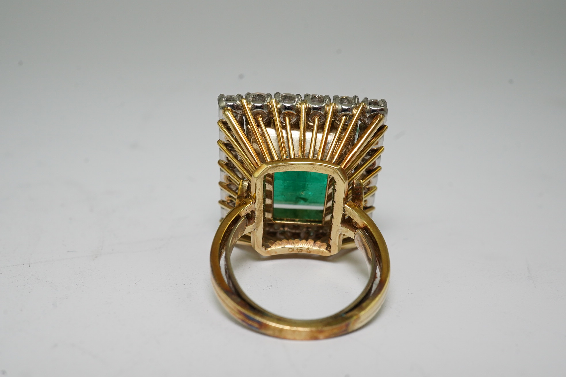 A Stern 18ct white and yellow gold, emerald and diamond dress ring, the central green emerald cut emerald approximately 8.0ct and surrounded by twenty two circular cut diamonds, approximately 2.7ct total